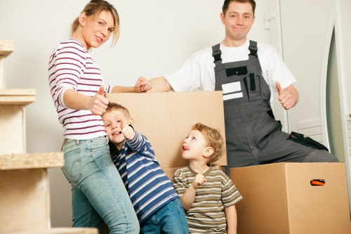 Removal crew carrying household items down stairs in a London property